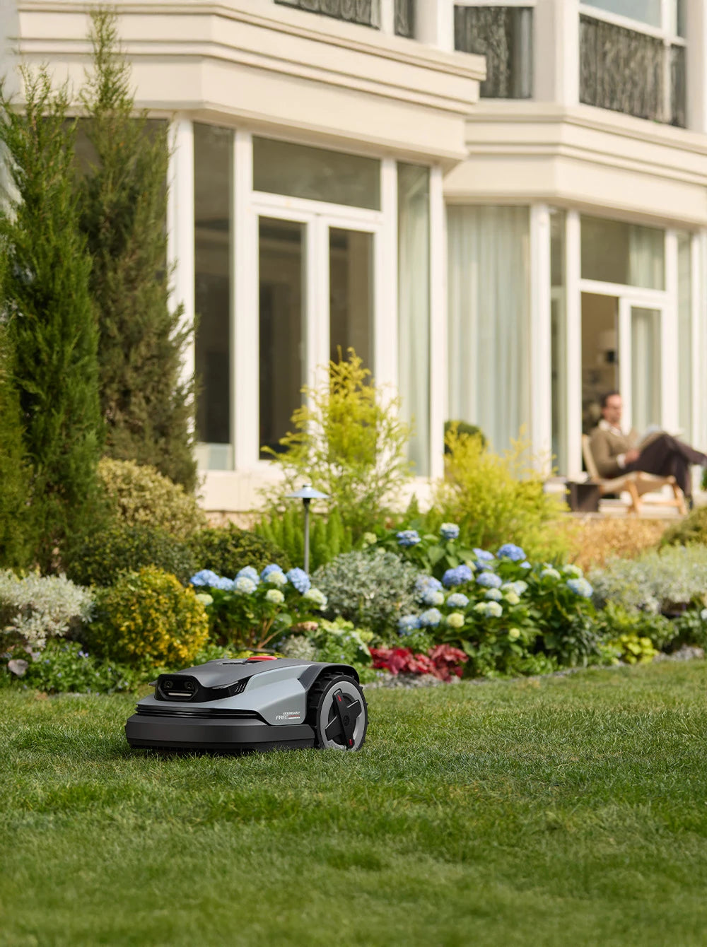 RockMow robotic lawn mower maintaining a garden lawn outside a modern home