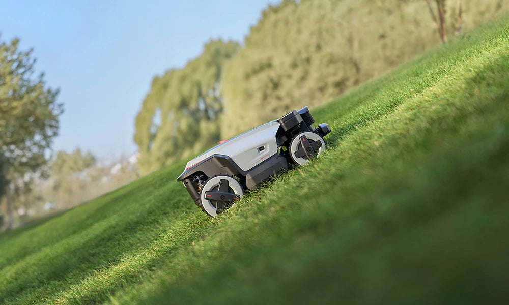 RockMow Z1 robotic lawn mower climbing a steep grassy slope using four-wheel drive.