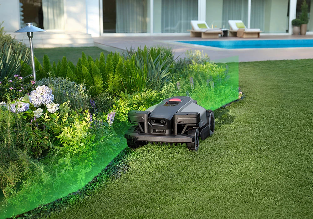 RockMow Z1 robotic lawn mower mapping the garden boundary beside a flower bed.