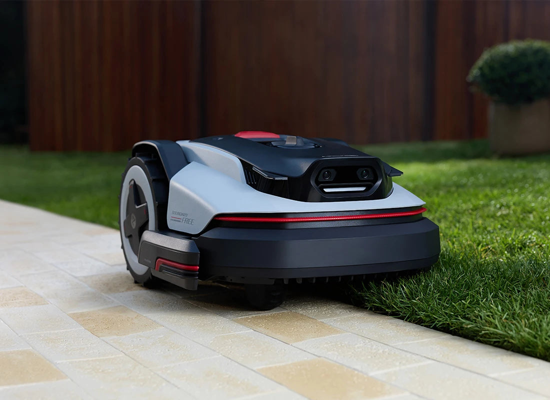 Robotic lawn mower on a patio edge with grass in the background